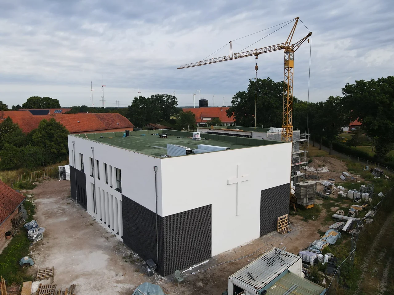 Die neue Kirche im Bau: die weiße Giebelwand mit dem großen Kreuz, daneben der Baukran