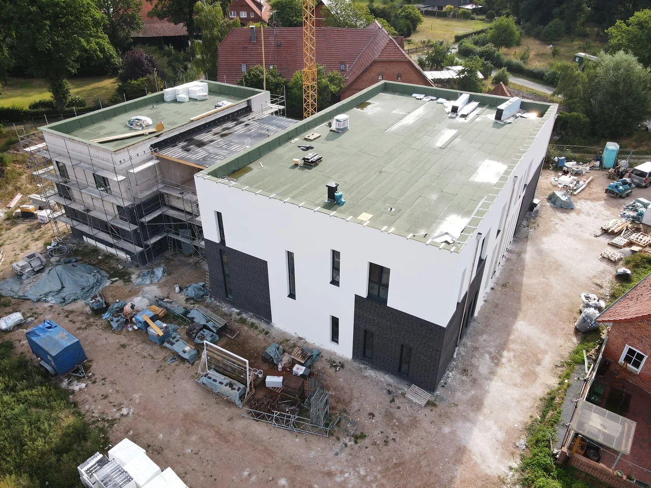 Luftbild des Neubaus in Anemolter: der große Saal, links der Anbau, ringsum das Dorf
